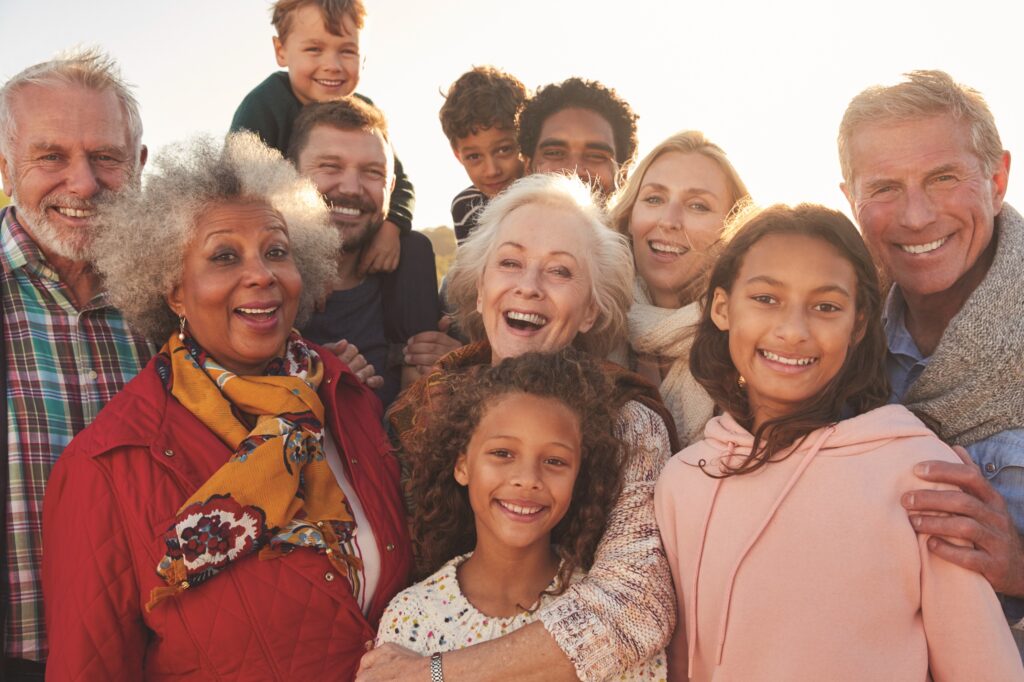 An intergenerational and intercultural group of people posing together joyfully.